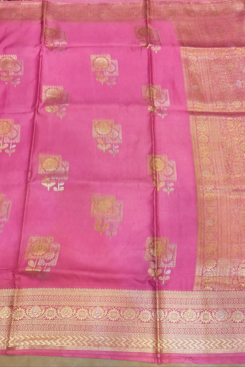 Pink saree with gold patterns on a plain background
