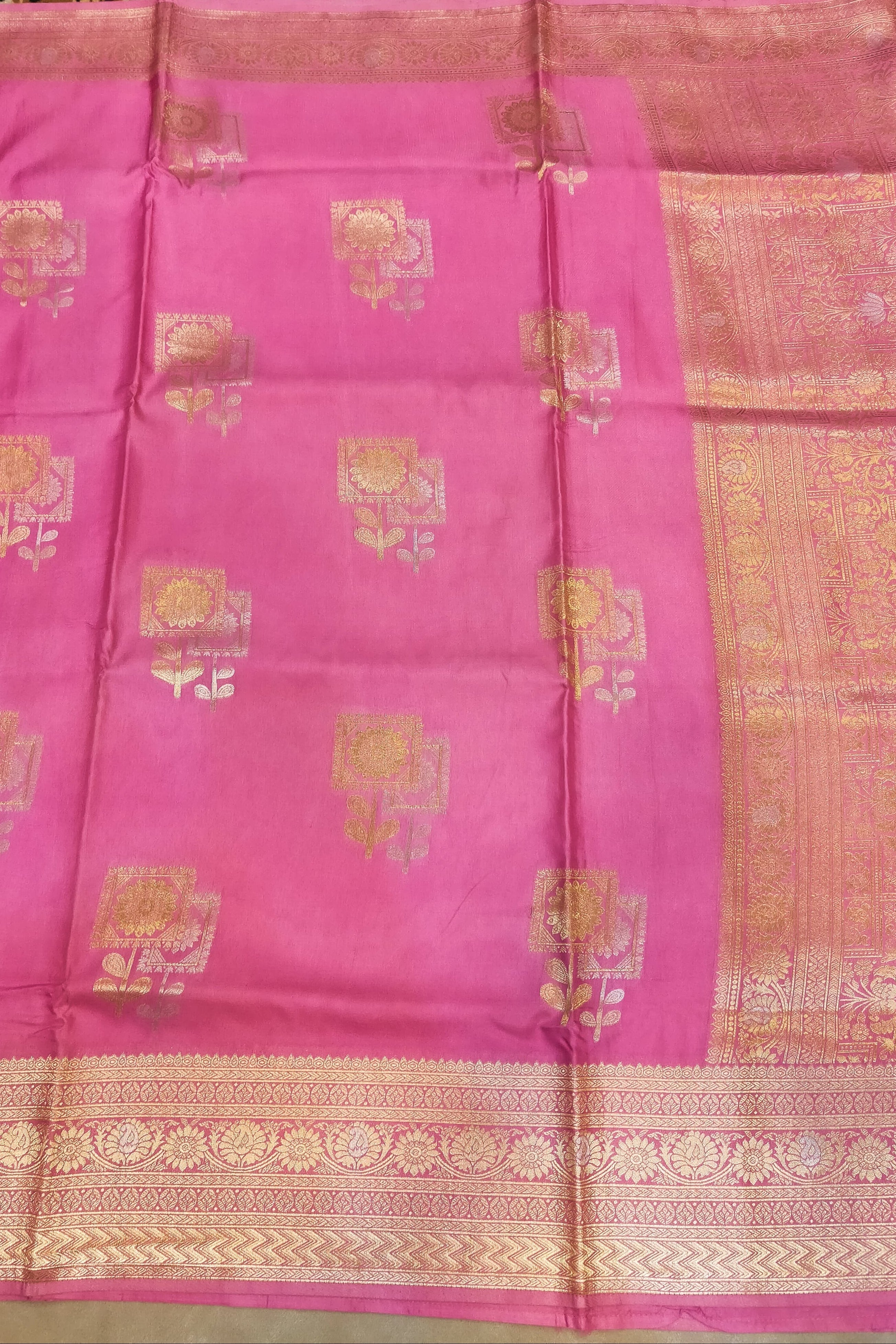 Pink saree with gold patterns on a plain background