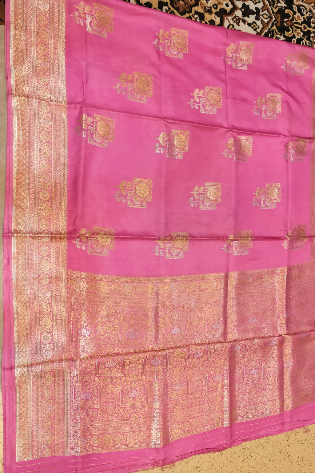 Pink saree with gold patterns on a plain background
