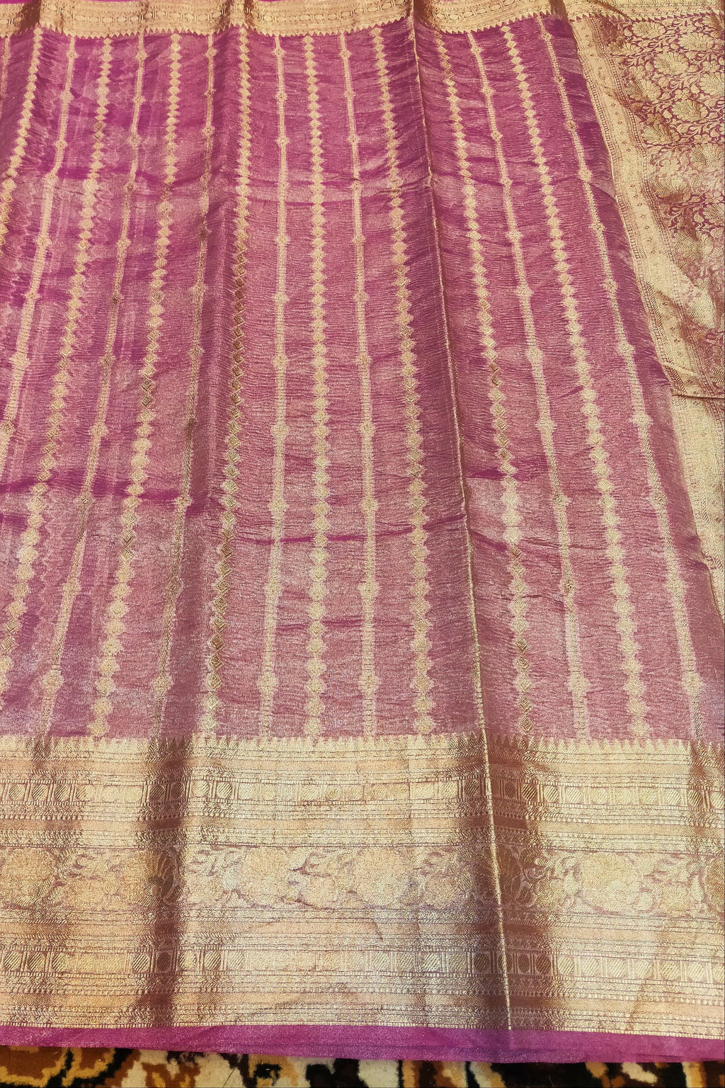 Purple and beige patterned fabric on a textured surface