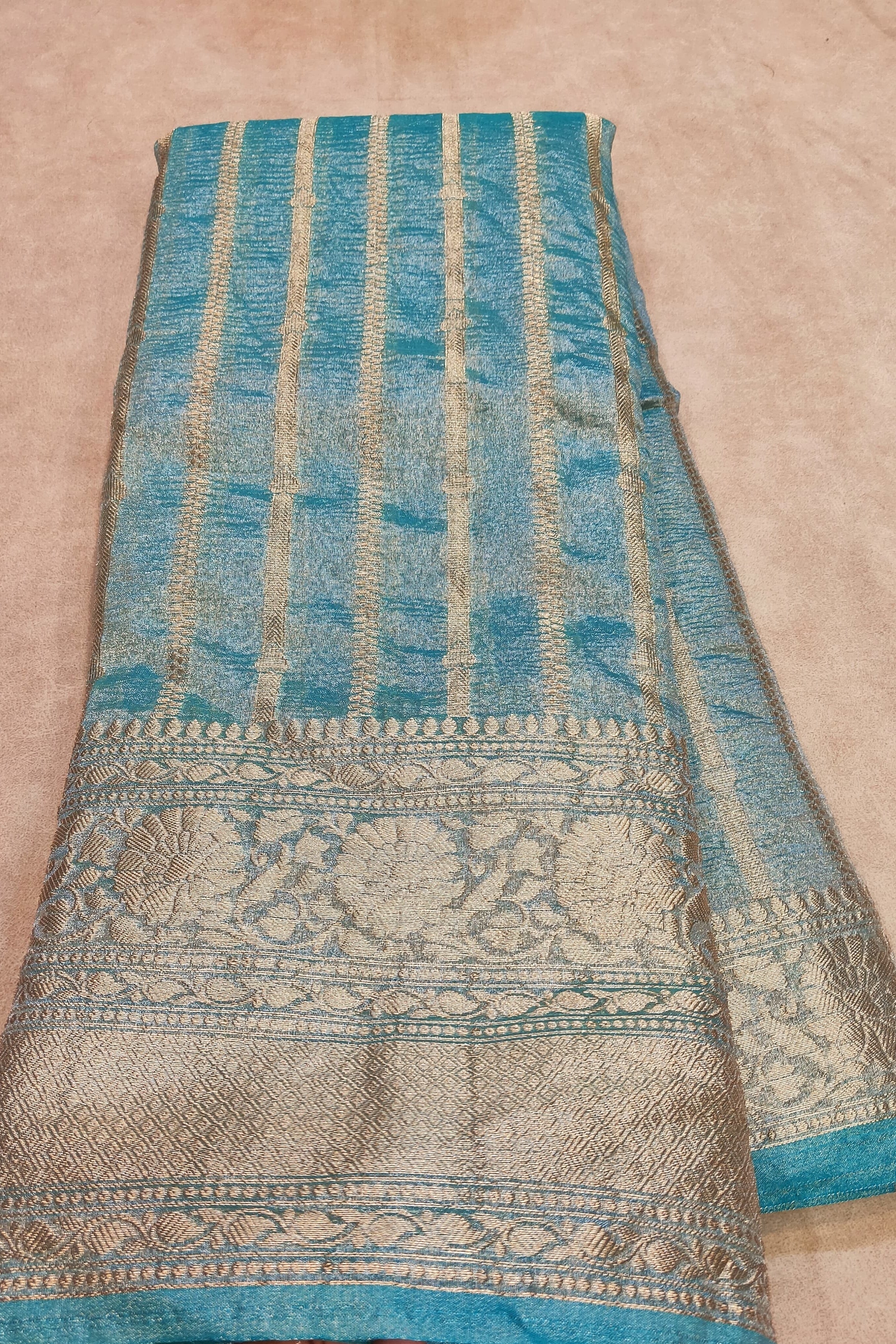 Folded fabric with blue and green patterns on a beige background