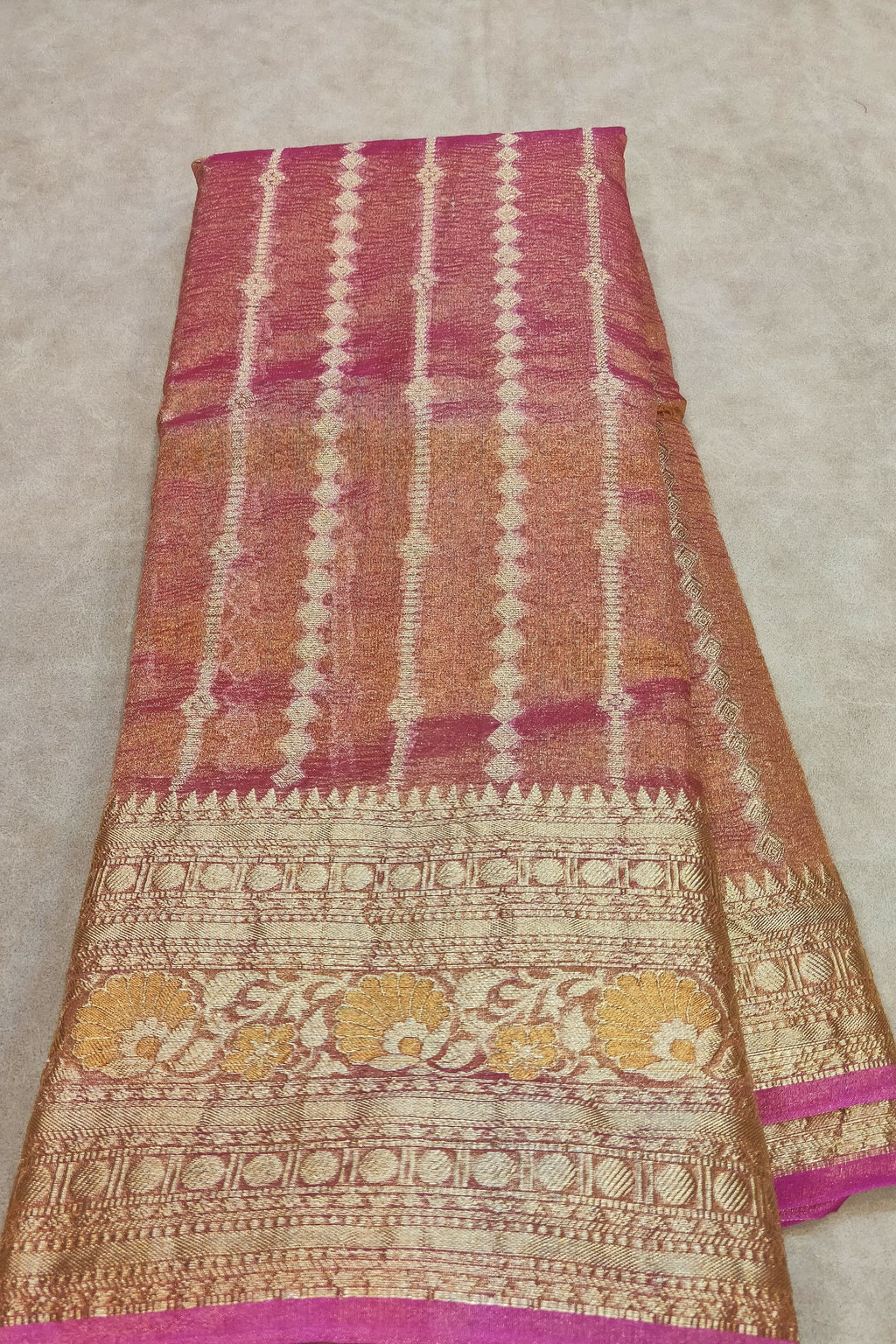 Traditional patterned fabric with pink, orange, and gold colors on a beige background