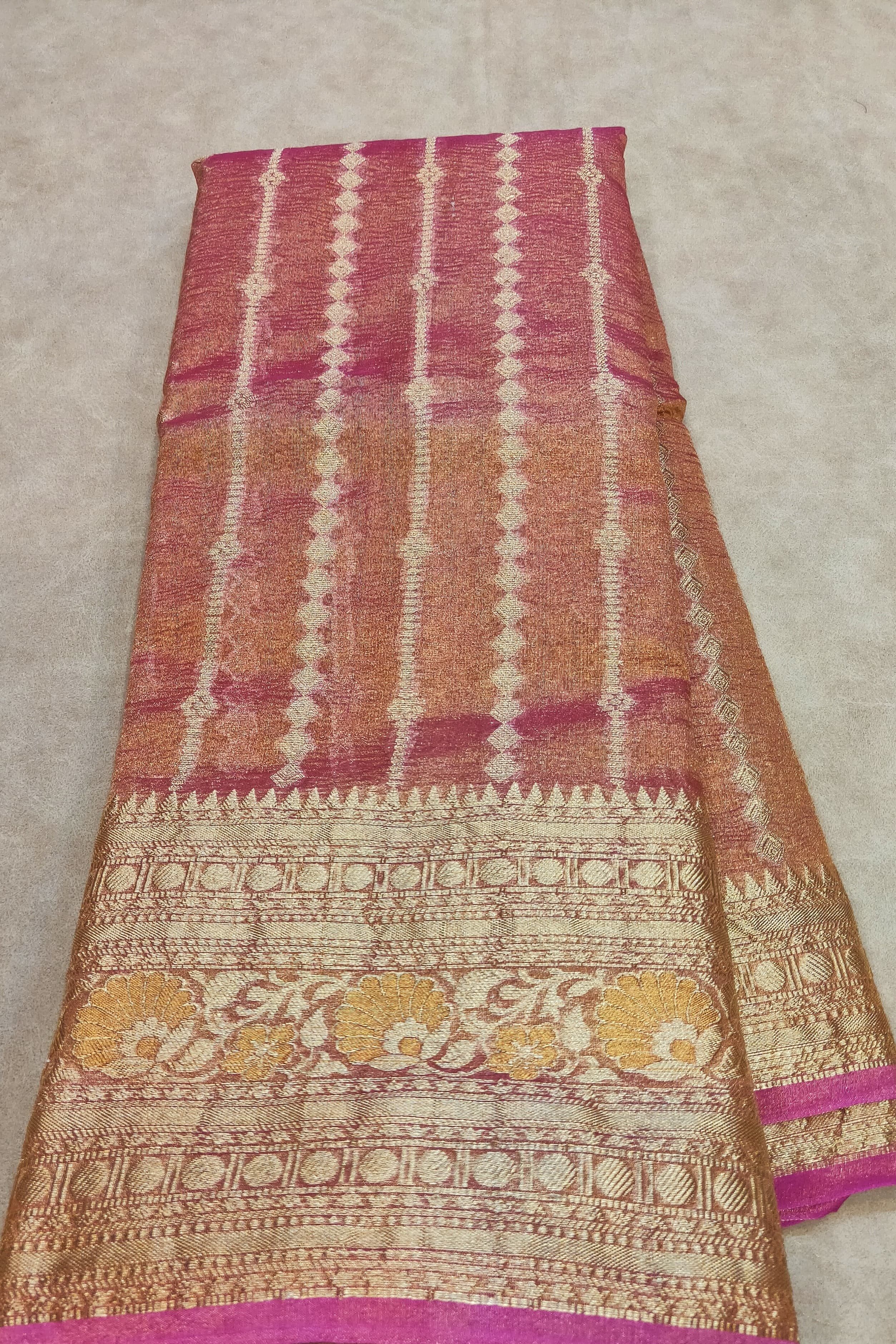 Traditional patterned fabric with pink, orange, and gold colors on a beige background
