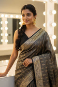 Woman in a traditional saree standing in front of a mirror with lights.