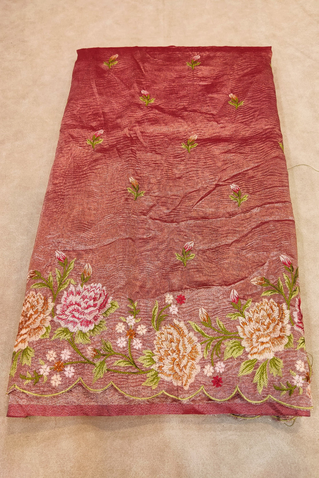 Red fabric with floral embroidery on a beige background