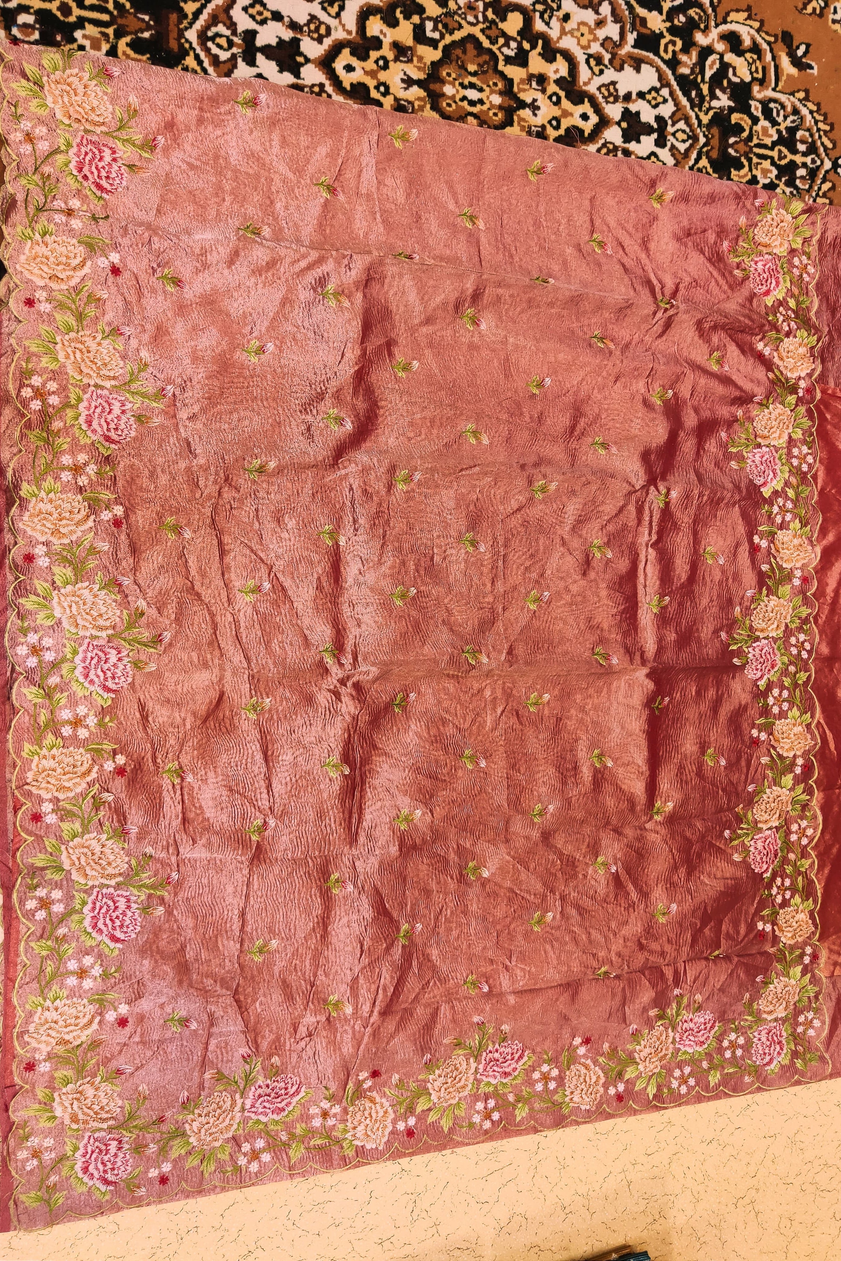 Pink fabric with floral patterns on a patterned carpet background