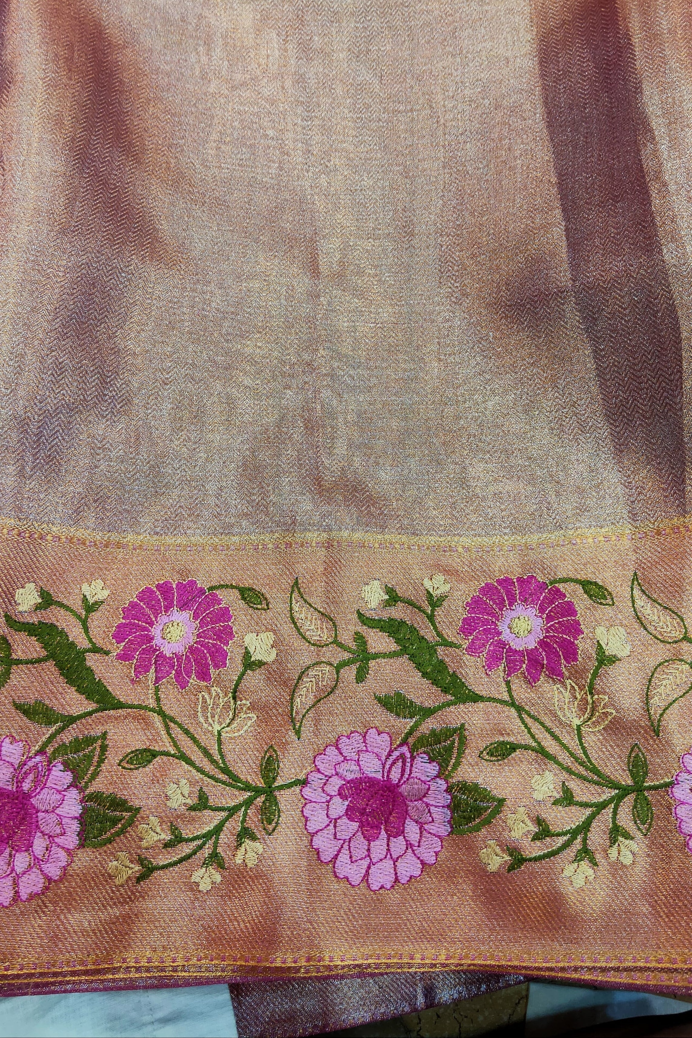 Brown fabric with pink floral embroidery on a green background