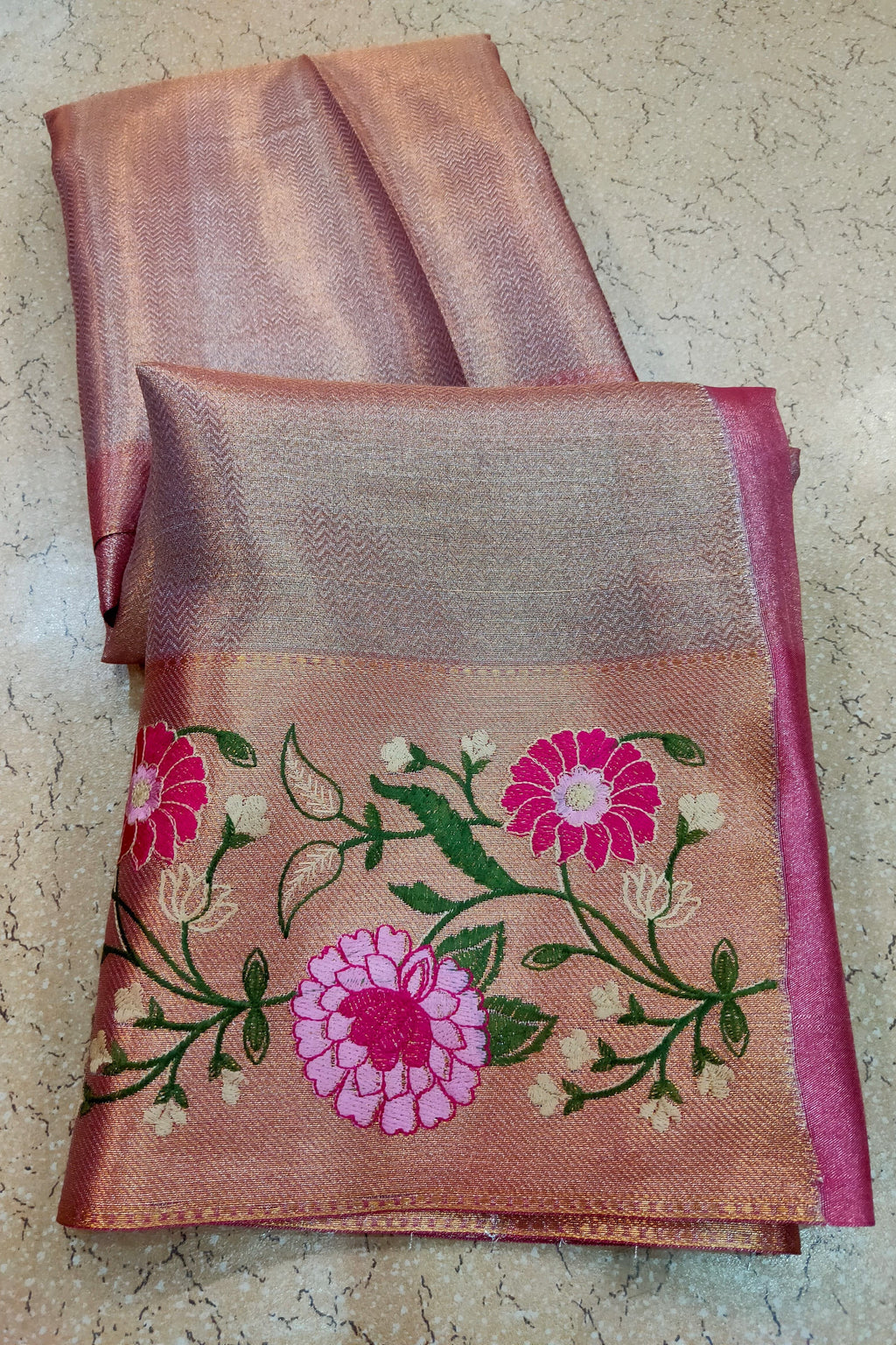 Folded saree with floral embroidery on a textured surface