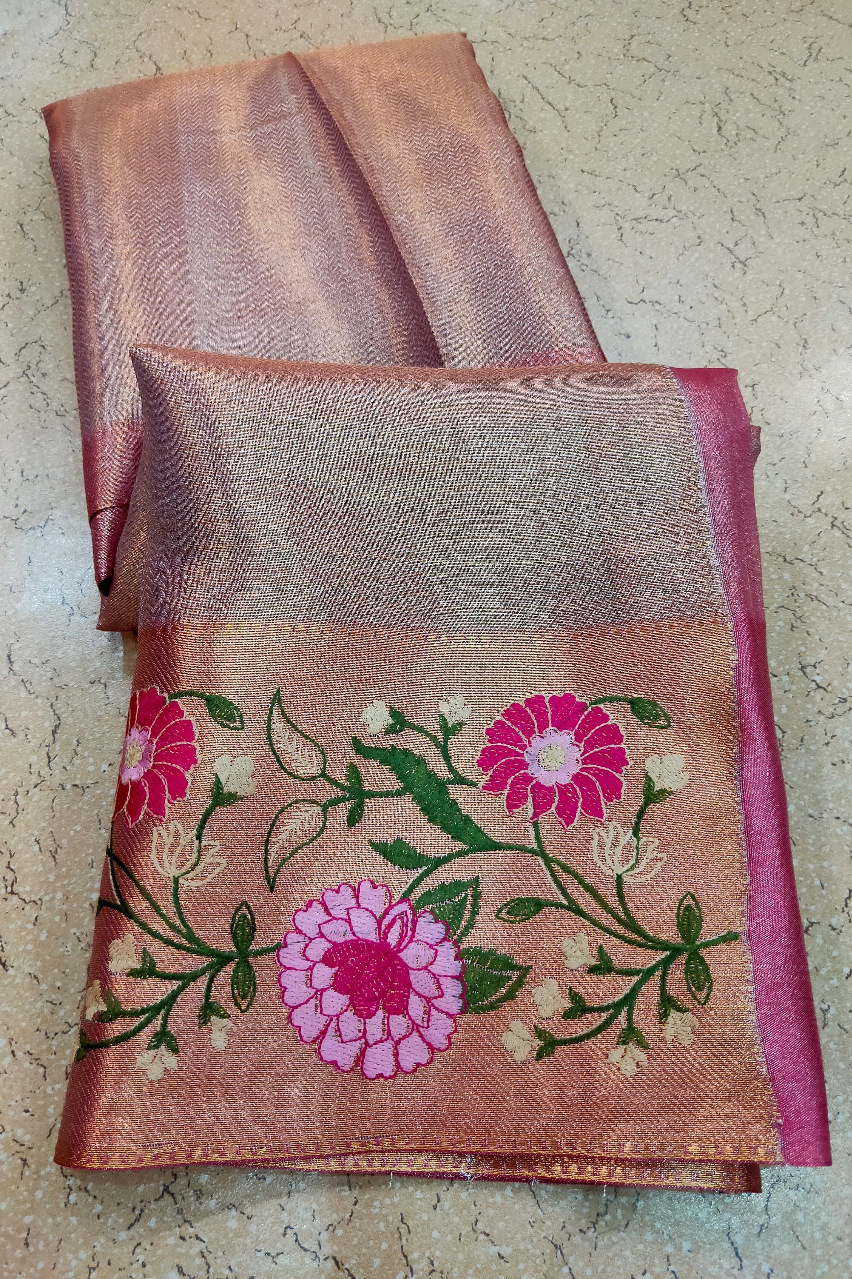 Folded saree with floral embroidery on a textured surface