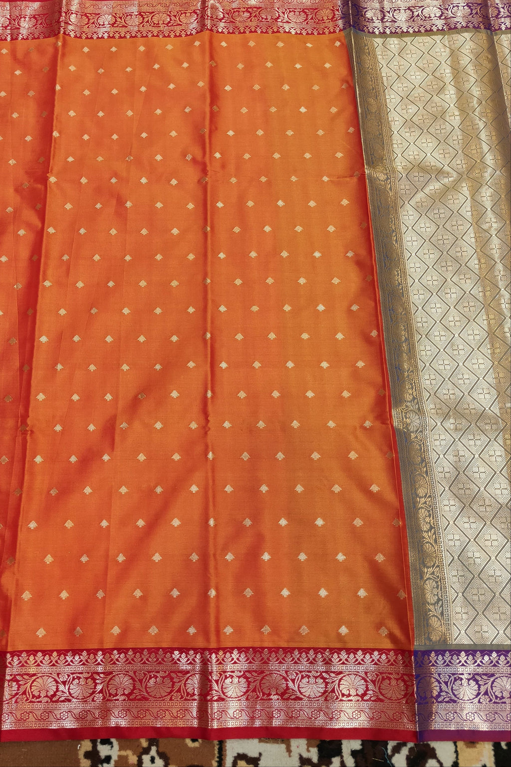 Orange saree with a patterned border on a textured fabric background