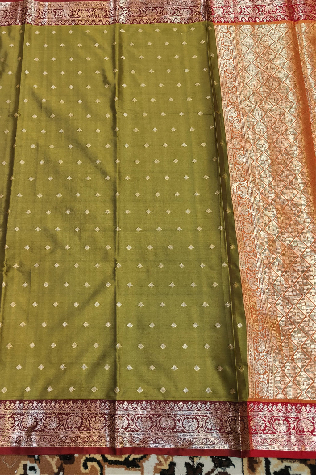 Green saree with white dot pattern and pink border on a patterned fabric background