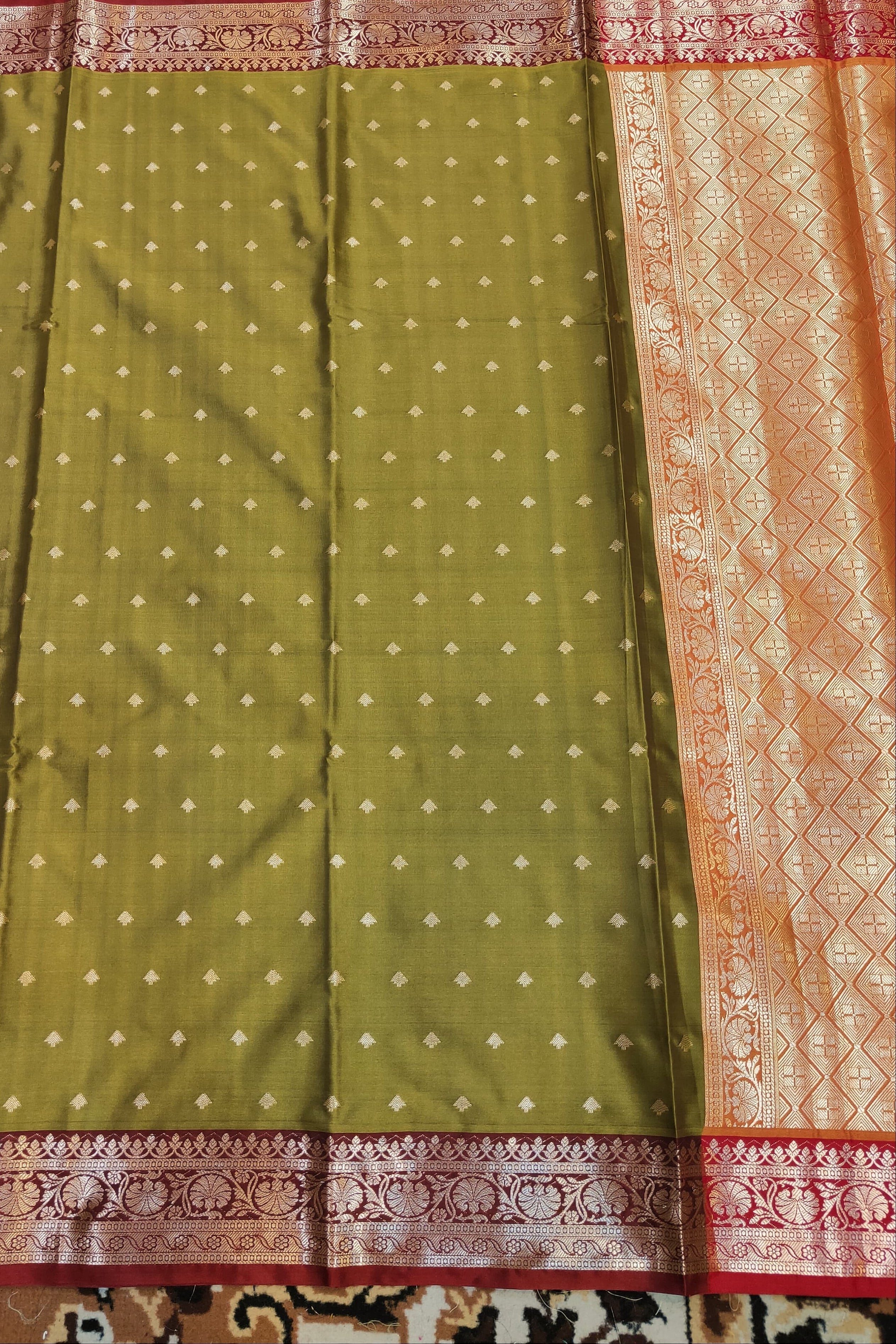 Green saree with white dot pattern and pink border on a patterned fabric background