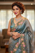 woman in a grey floral saree indoors