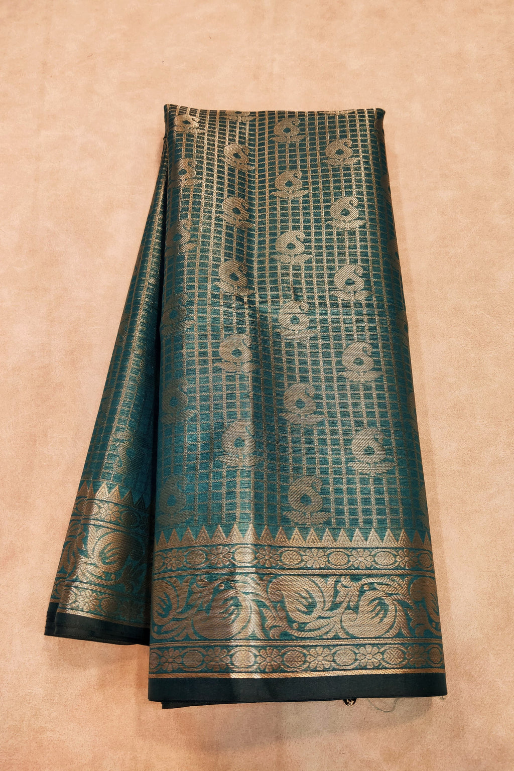 Teal and gold patterned fabric on a beige background