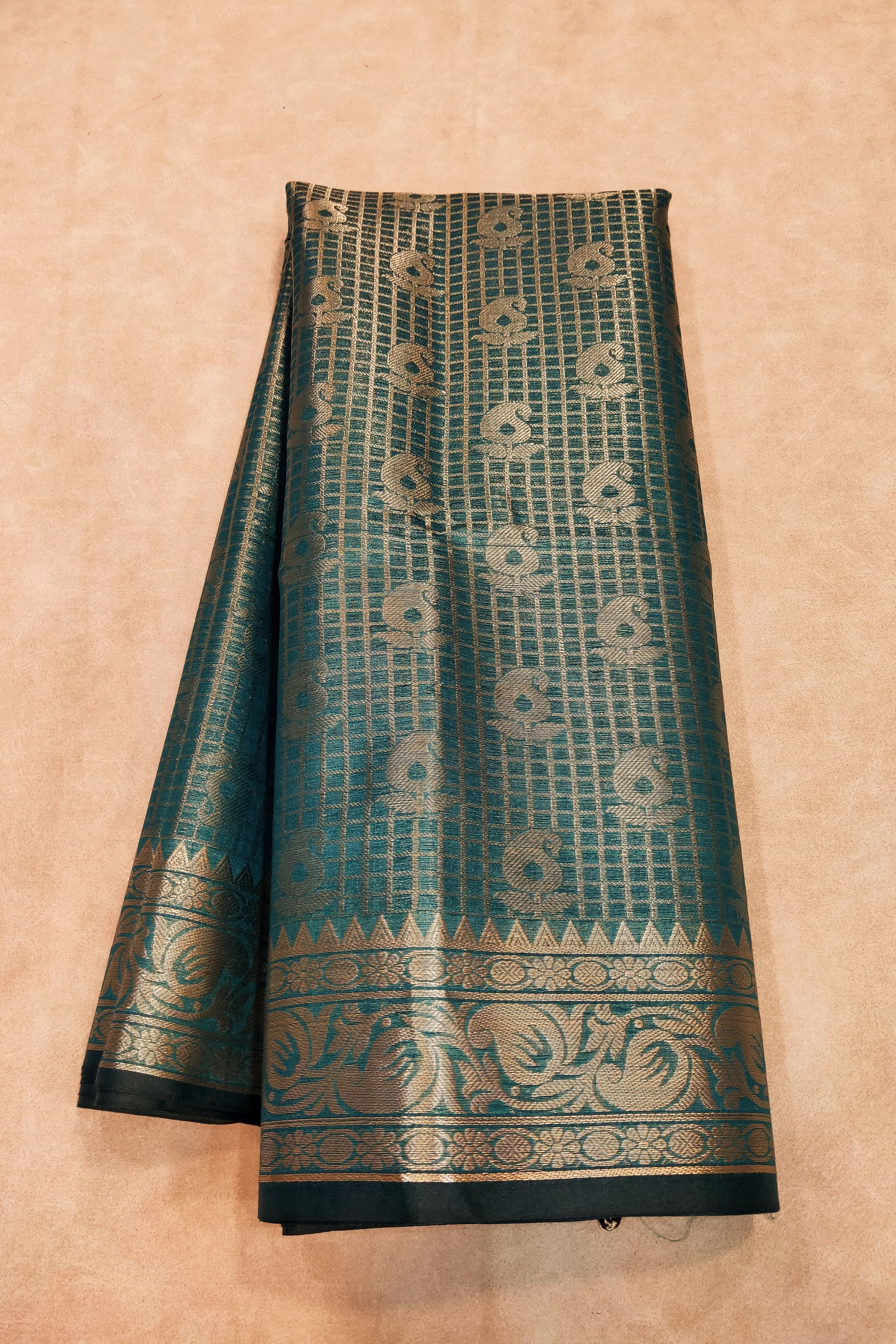 Teal and gold patterned fabric on a beige background