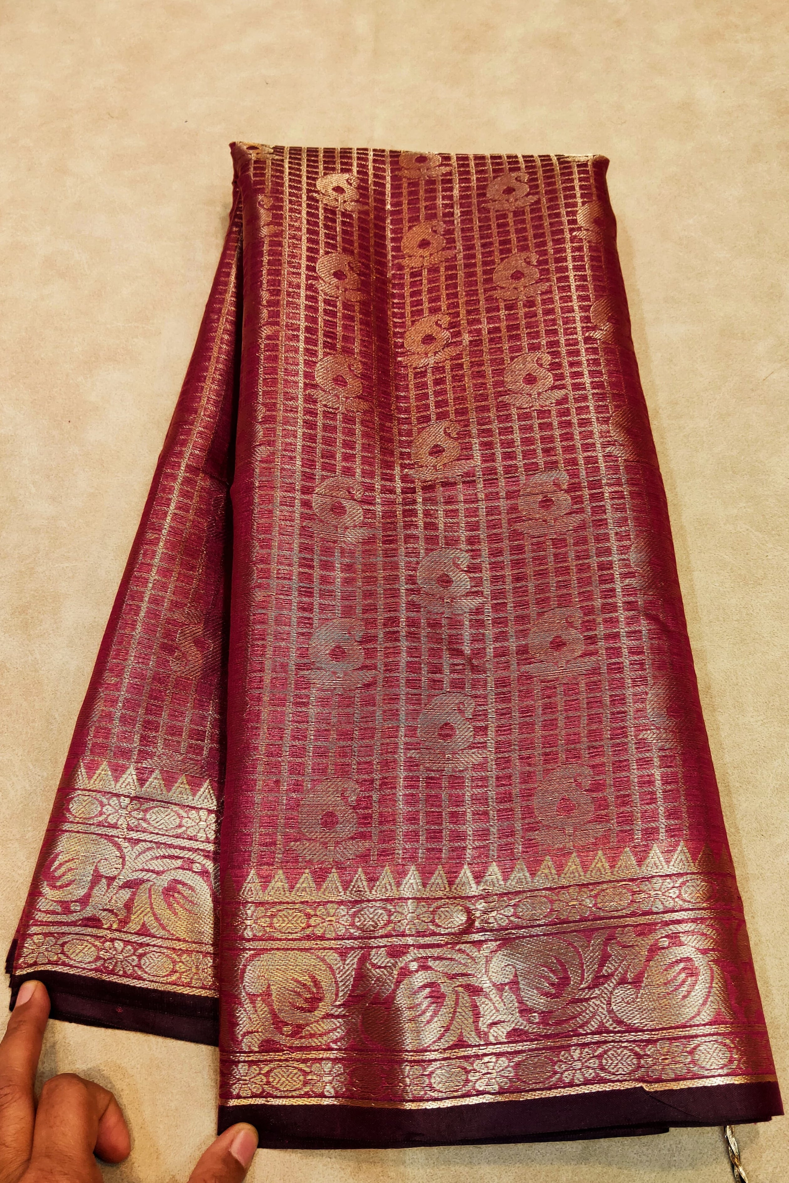 Maroon saree with gold patterns on a beige surface
