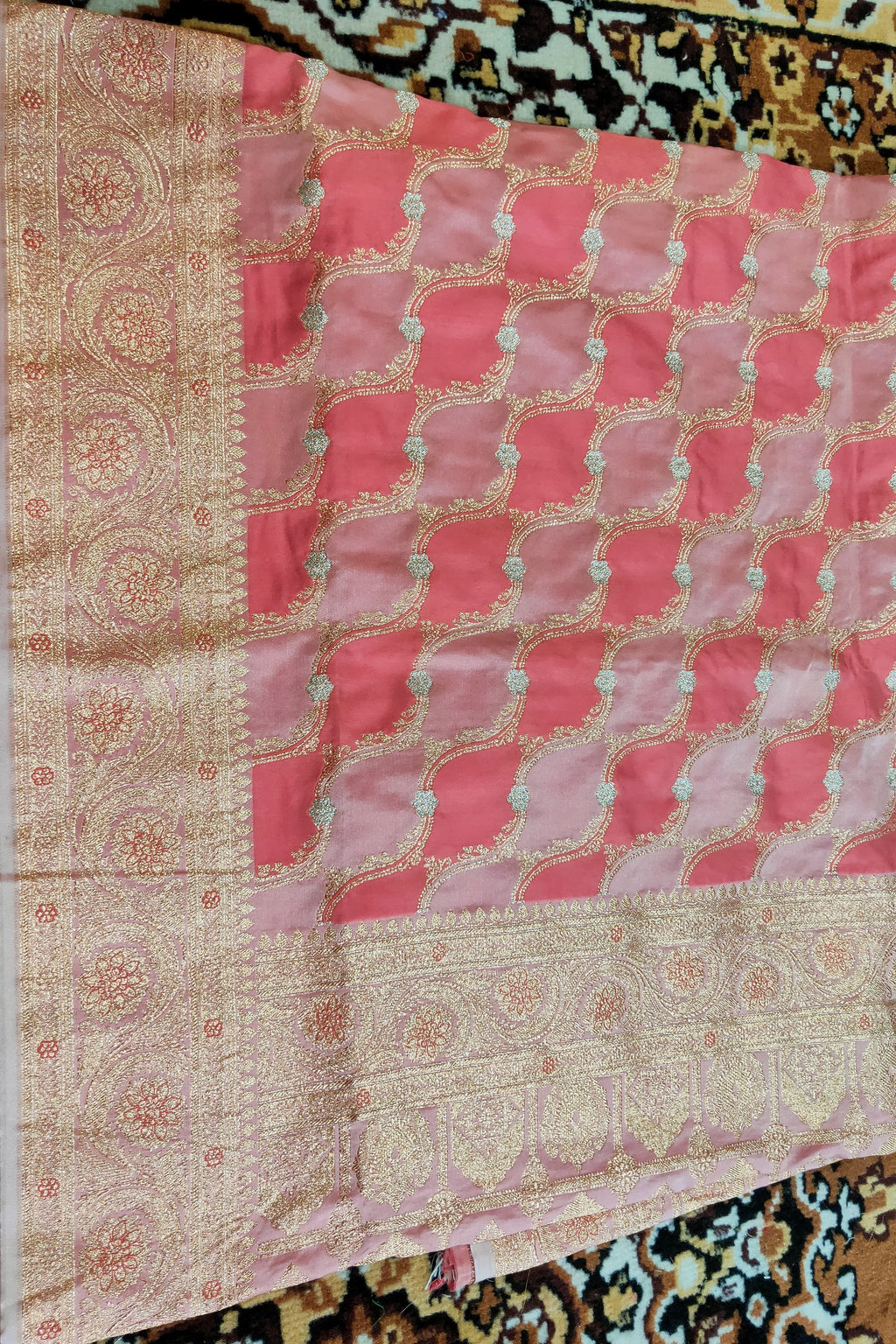 Decorative pink and beige fabric with intricate patterns on a patterned background
