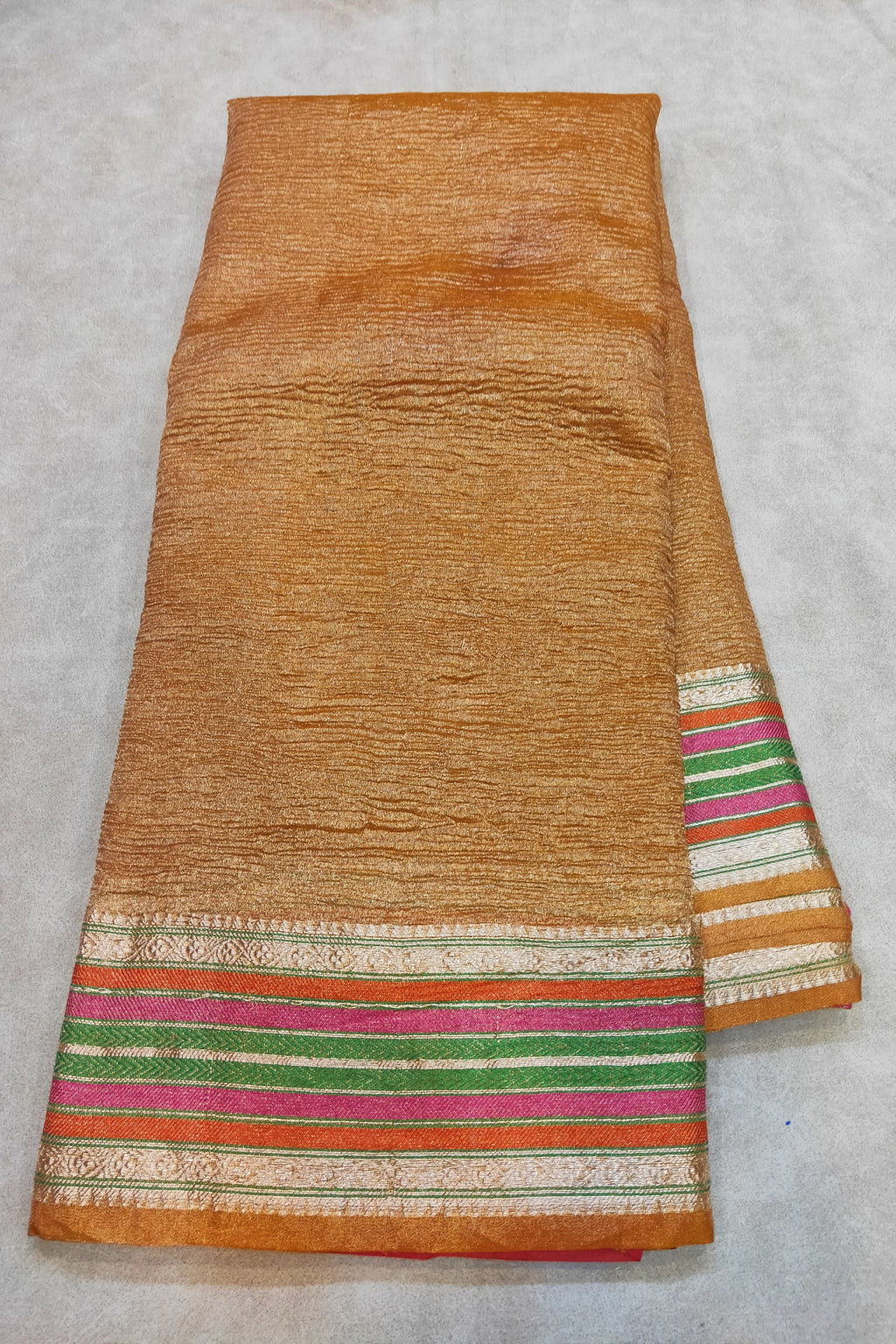 Textured fabric with colorful striped border on a light gray background