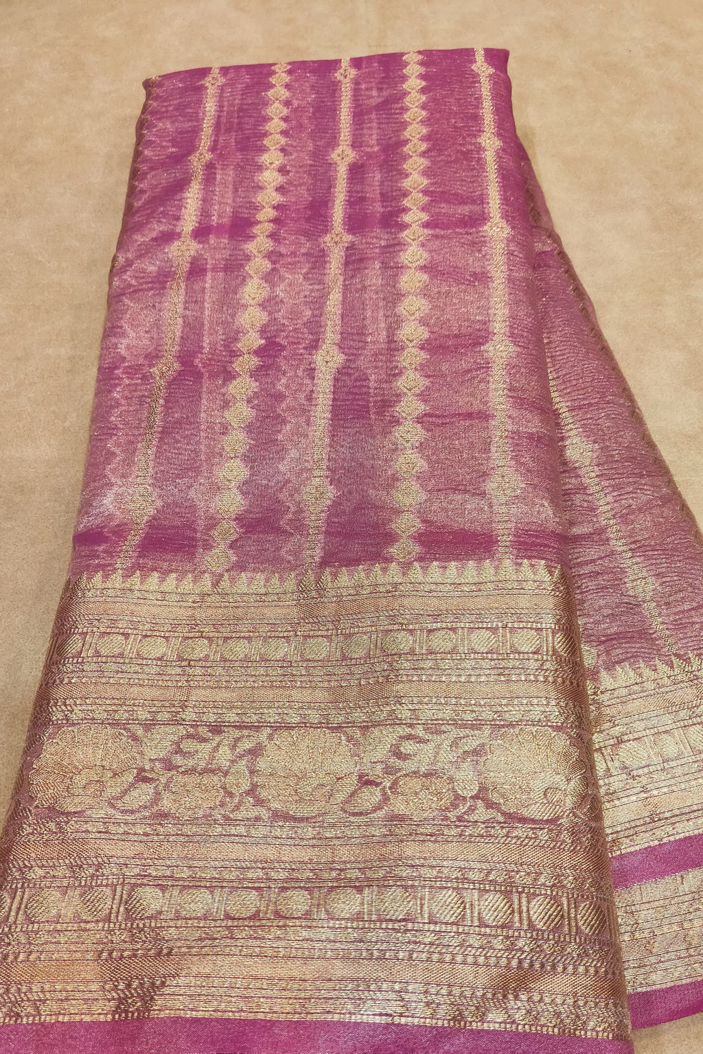 Purple and beige patterned fabric held by a hand on a beige background
