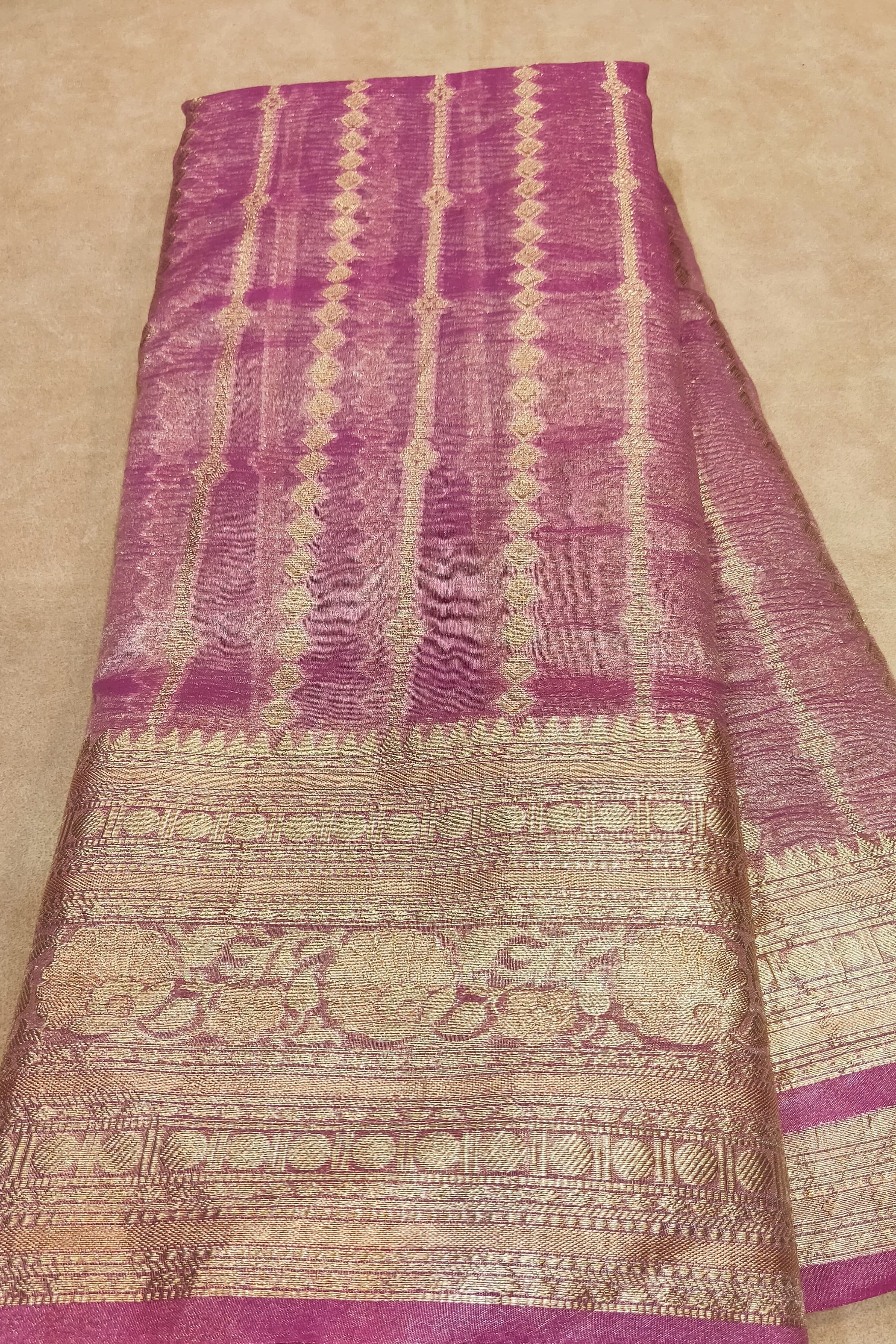 Purple and beige patterned fabric held by a hand on a beige background