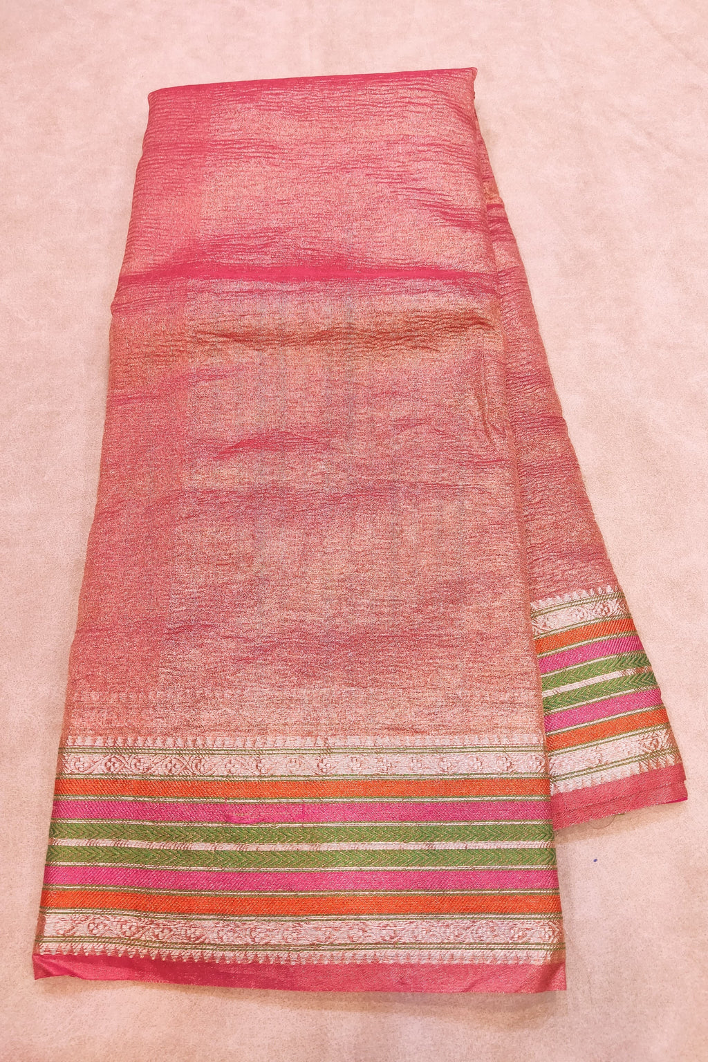Traditional fabric with pink and multicolor border on a light pink background