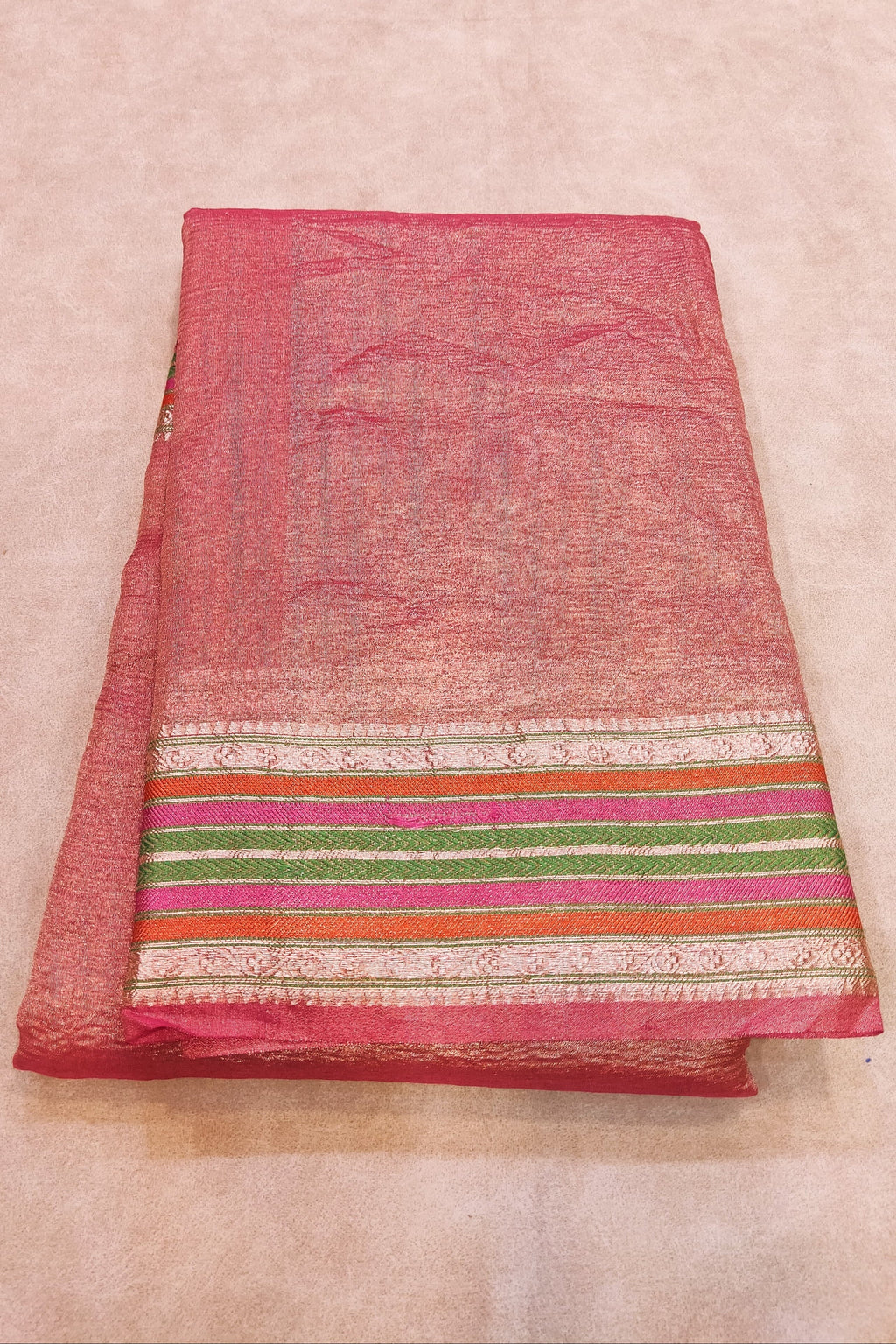 Pink fabric with colorful stripes on a beige background