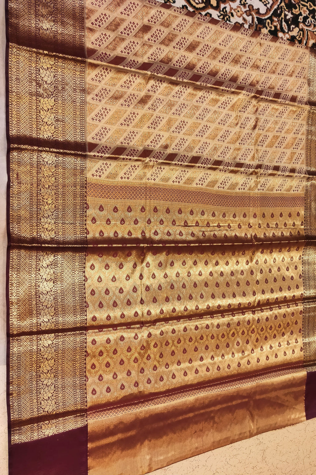 Brown and gold patterned fabric with intricate designs on a plain background