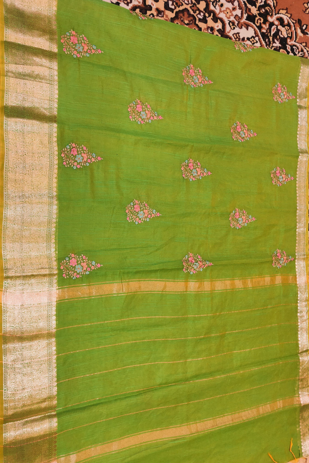 Green saree with floral patterns on a patterned background