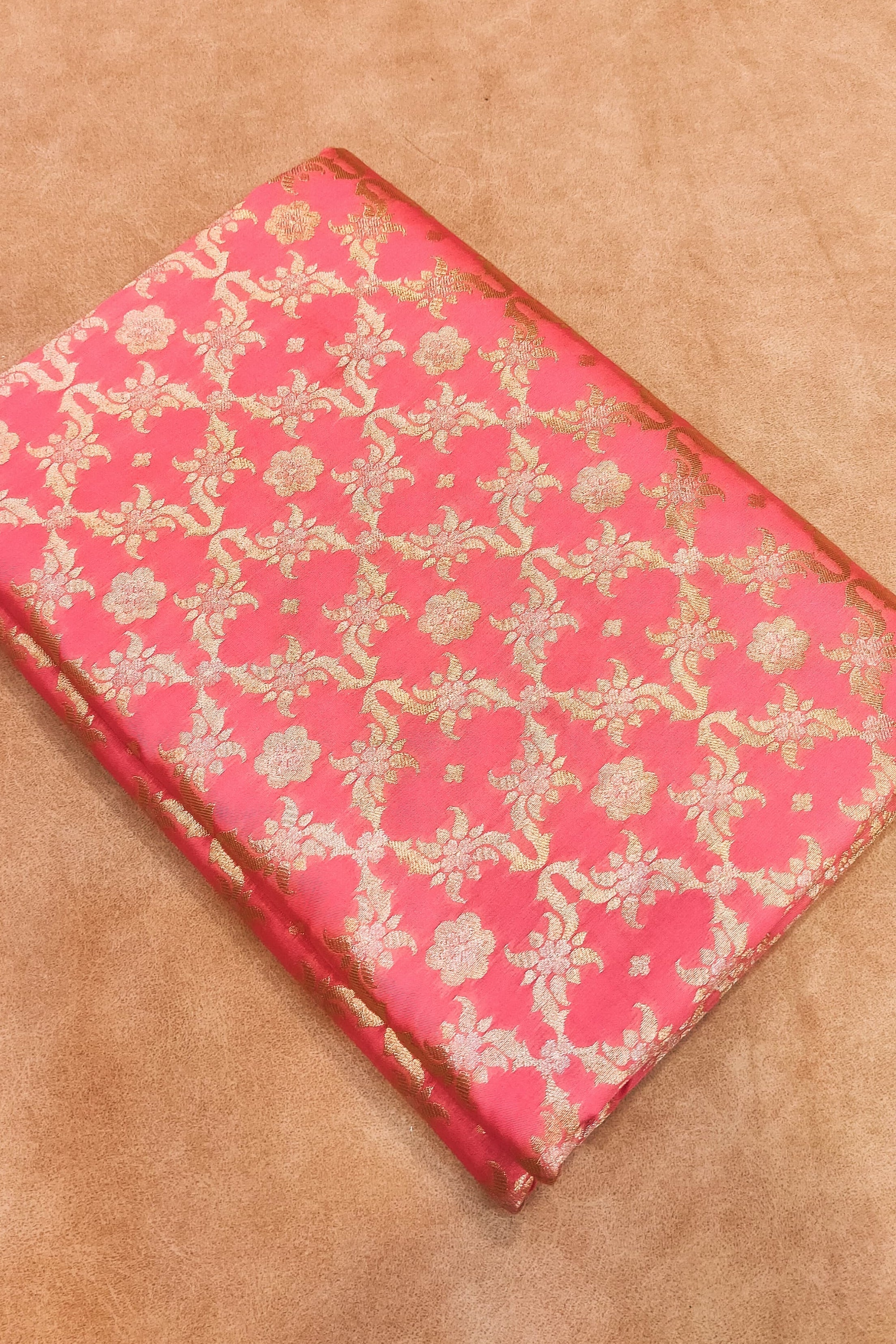 Pink fabric with gold floral patterns on a beige background