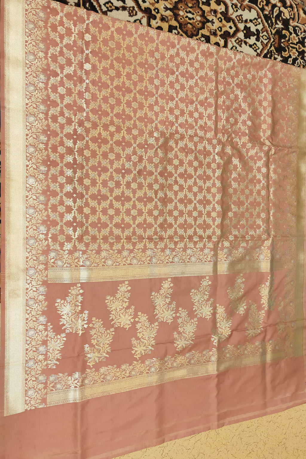 Pink saree with intricate white patterns on a textured surface