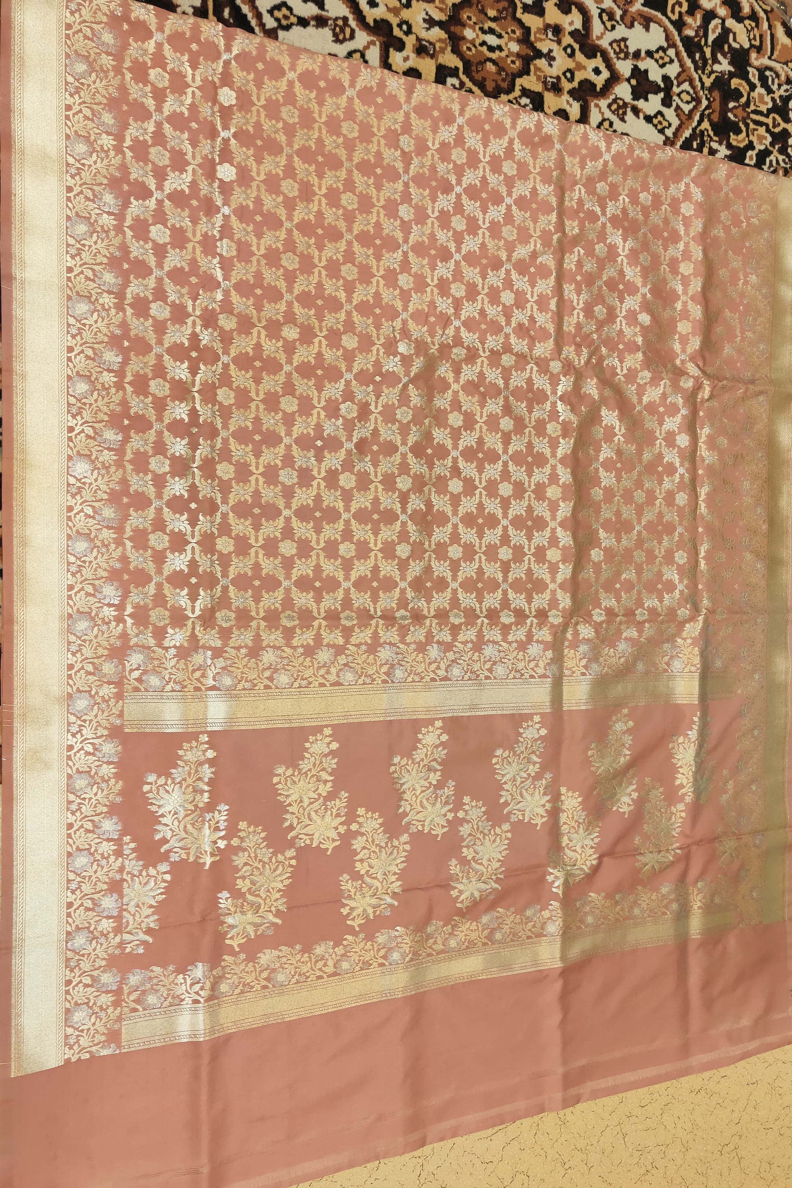 Pink saree with intricate white patterns on a textured surface