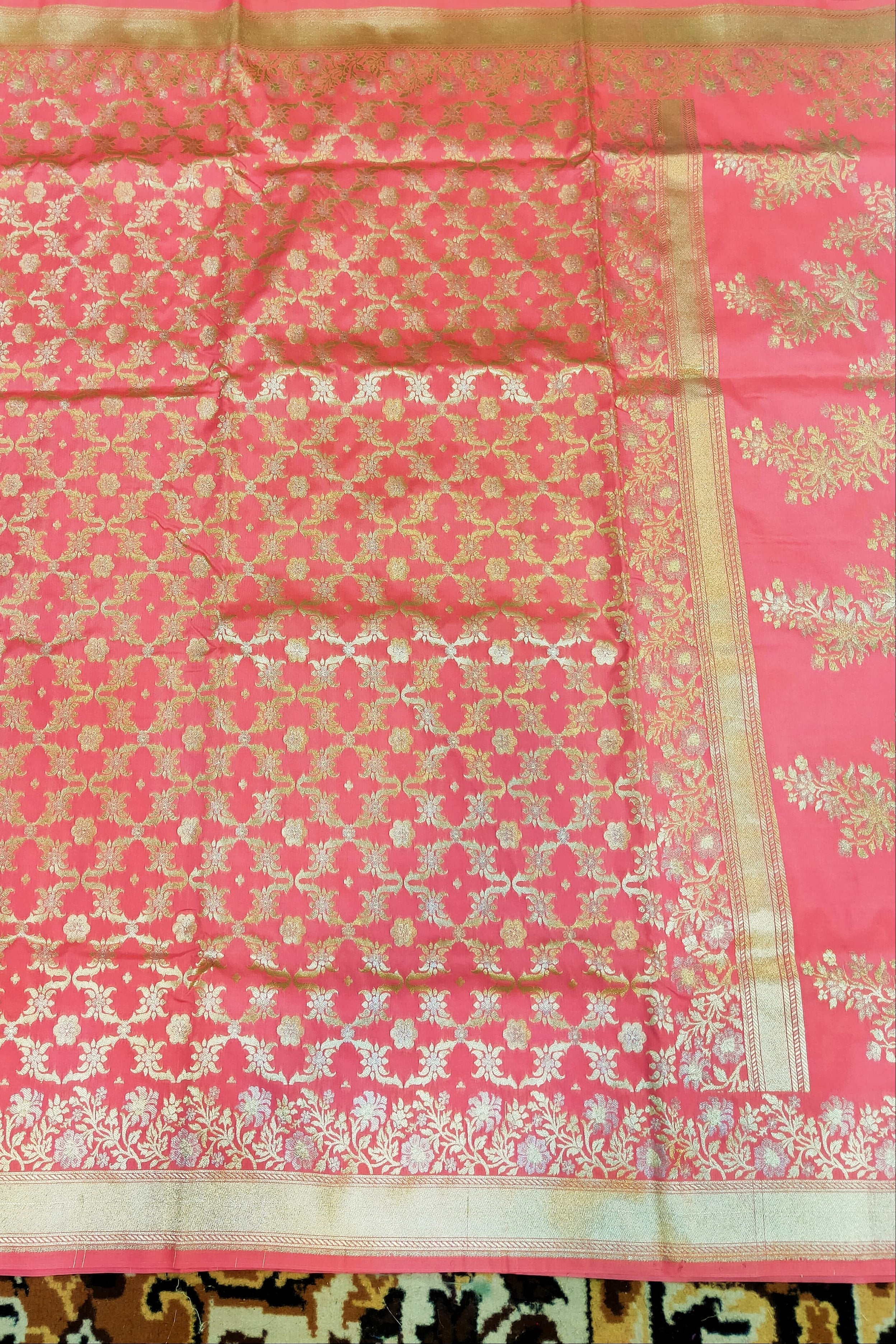 Pink saree with white floral patterns on a patterned background