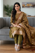 Woman in traditional attire sitting on a gray couch in a living room.