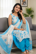 Woman in a blue and white traditional outfit sitting on a gray couch.