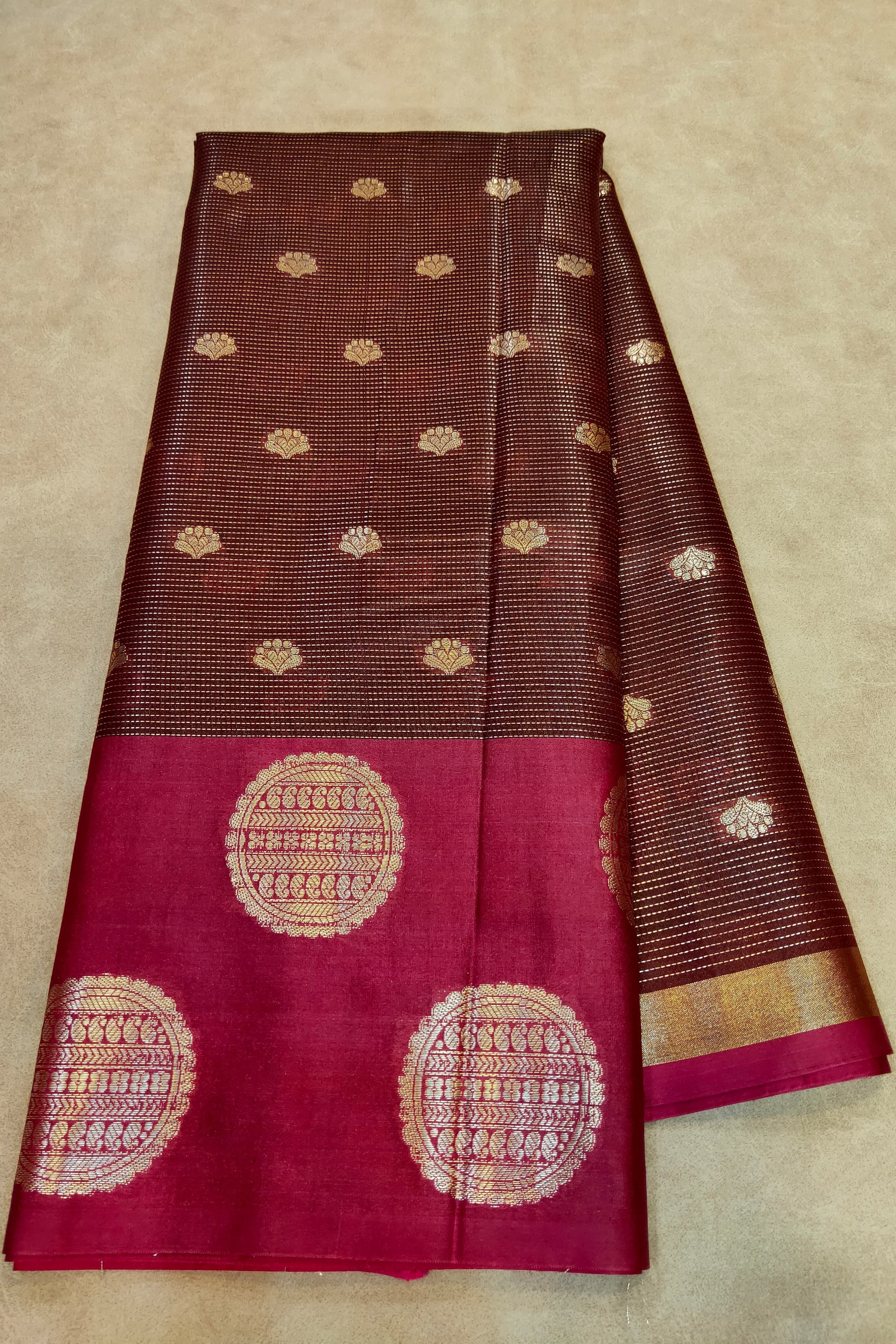 Brown and red saree with gold patterns on a beige background