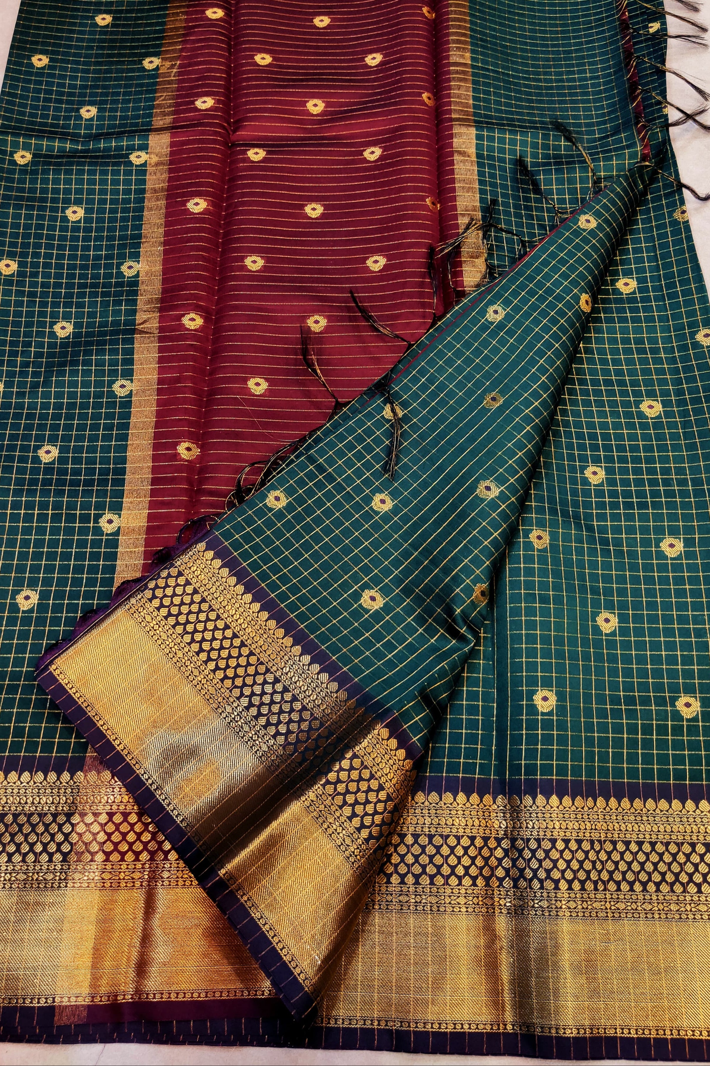 Green and maroon saree with gold patterns on a white surface