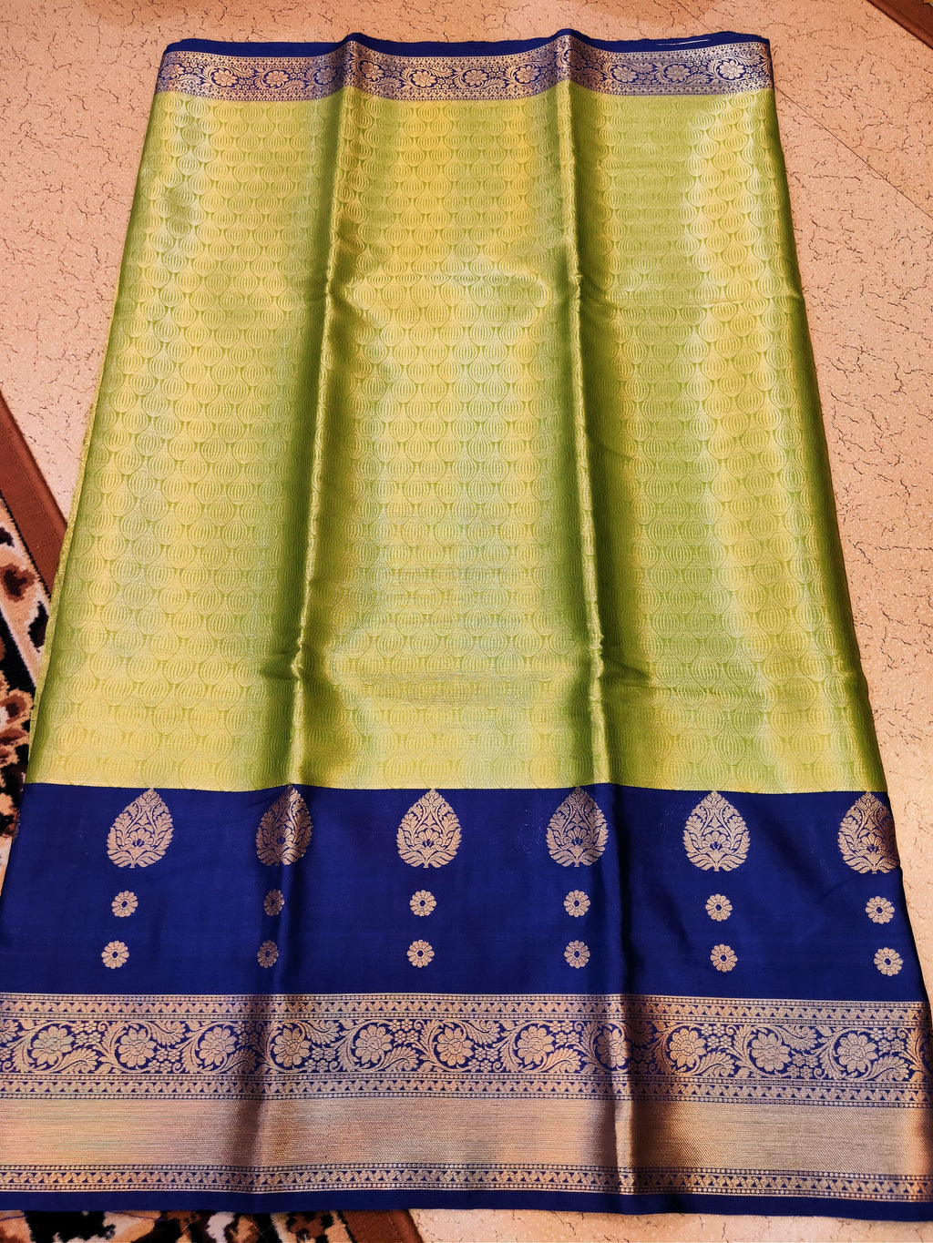 Green and blue saree with intricate patterns on a beige background