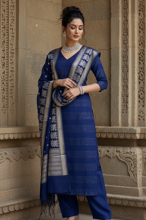 Woman in a blue traditional outfit standing against an architectural background