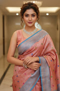 Woman in a pink saree with a blue border indoors