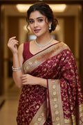Woman wearing a maroon saree with gold patterns indoors