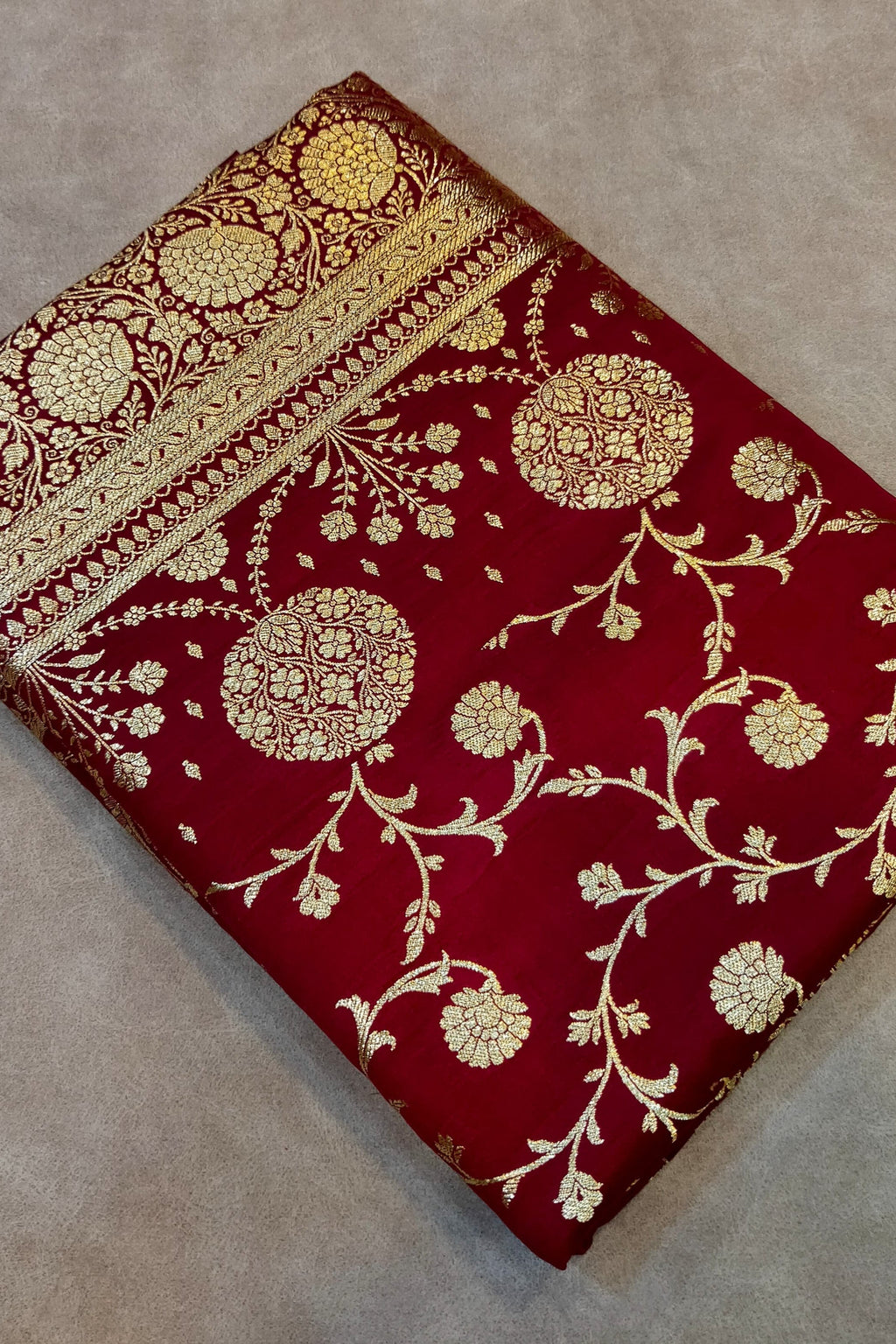 Red fabric with gold floral patterns on a beige surface