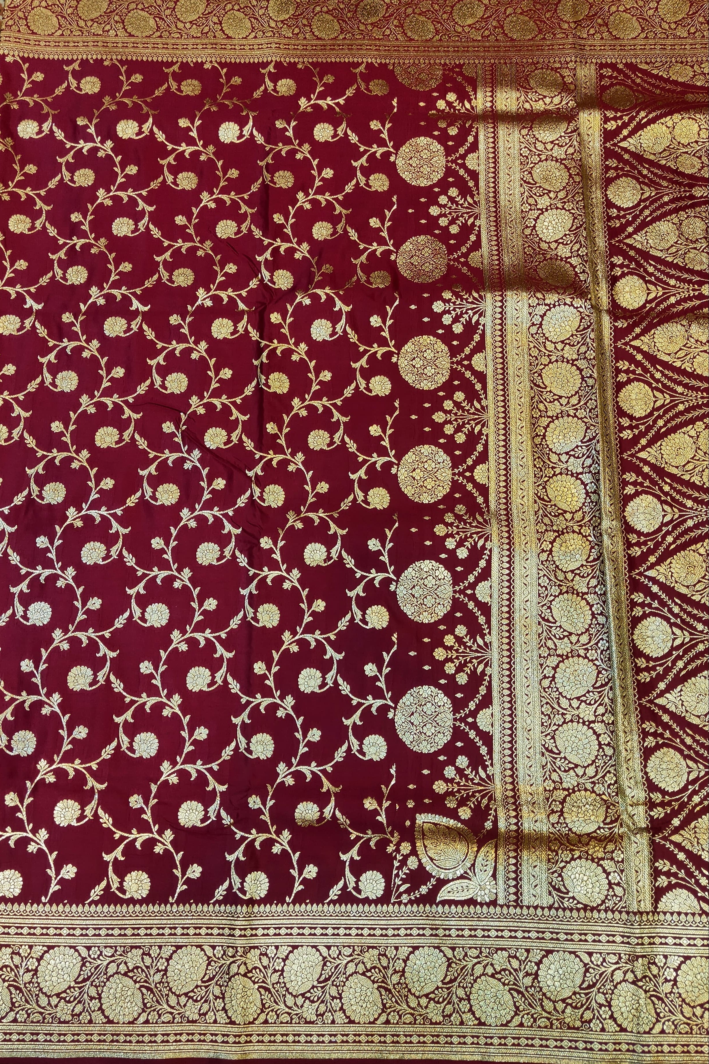Maroon fabric with gold intricate patterns on a textured surface
