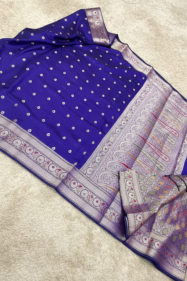 Blue saree with white polka dots and intricate border on a light gray background