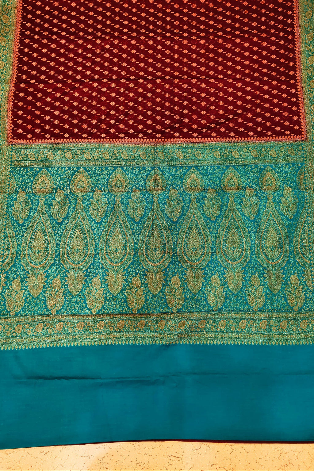 Teal and red fabric with intricate patterns on a patterned background